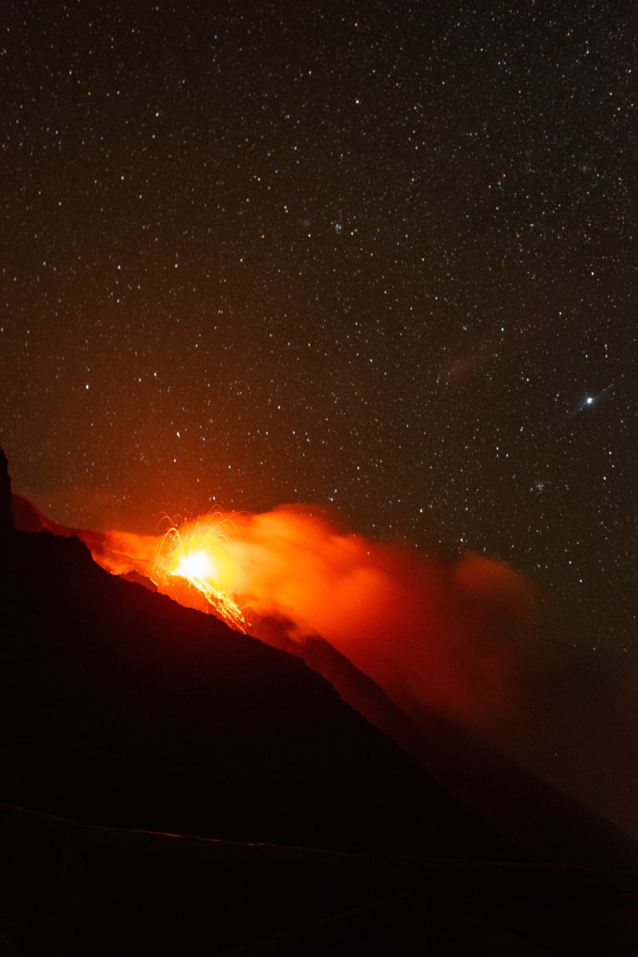 Active volcano erupting glowing lava beneath a star-filled night sky